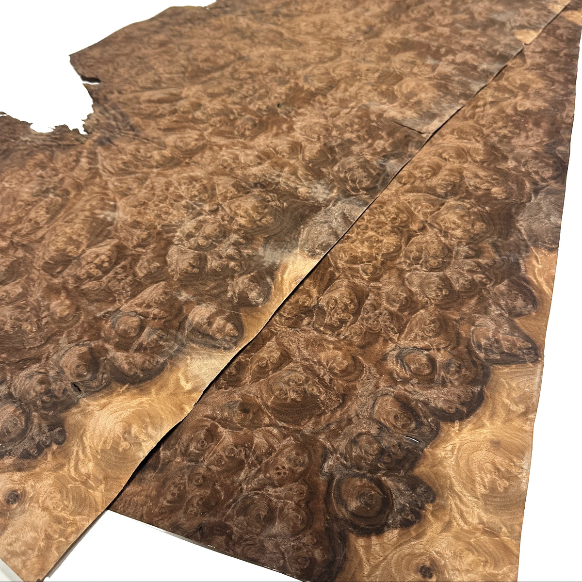 Two large pieces of burl wood veneer sheets with dramatic swirling grain patterns, displayed diagonally on a white background.